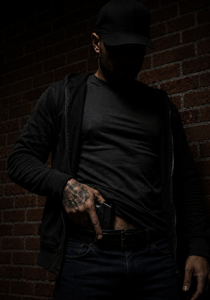 Shadowed person revealing handgun in waistband